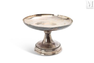 une petite assiette en argent posée sur un socle, sur fond blanc