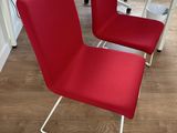 two red chairs sitting next to each other on a wooden floor