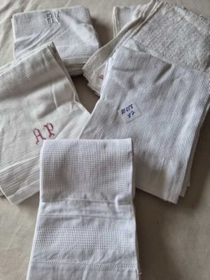 trois serviettes blanches ornées de monogrammes brodés, posées sur un lit