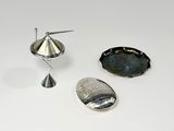 un objet argenté posé sur une surface blanche, à côté d'un autre objet argenté