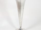 a silver vase that is sitting on a white surface
