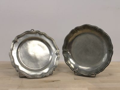 une paire de porte-assiettes en métal argenté posés sur une table en bois, sur fond blanc