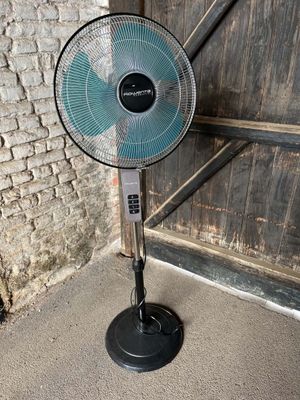 a fan that is sitting on the floor in front of a brick wall