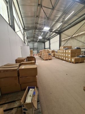 un grand entrepôt où s'entassent de nombreuses caisses par terre