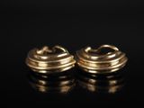 une paire de boucles d'oreilles en or sur une surface noire