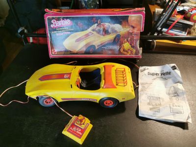 une petite voiture jaune posée sur une table, à côté d'une boîte de jouets