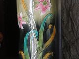 a vase that has flowers painted on it on a shelf