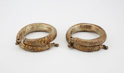 a pair of gold bracelets on a white surface