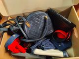 une boîte remplie de sacs à main et de sacs à bandoulière posée par terre