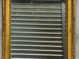 an antique gold framed mirror with a metal shutter in the middle