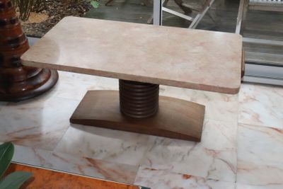 a marble table with a wooden base in the middle of a room
