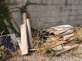 a pile of wood on the ground next to a wall