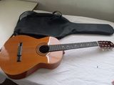une guitare posée sur un lit, avec son étui