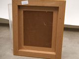 an empty picture frame sitting on the floor in front of a white wall
