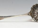 silver spoon with a flower design on it sitting on a white surface