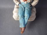 a figurine of a man sitting on a rock with his hands in his pockets
