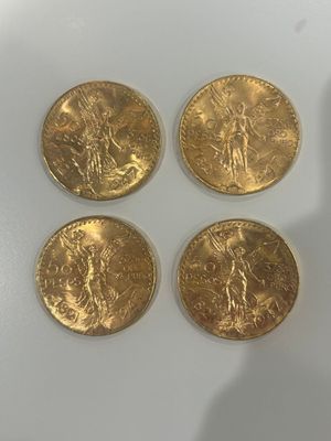 quatre pièces d'or posées sur une table, à côté d'un téléphone portable