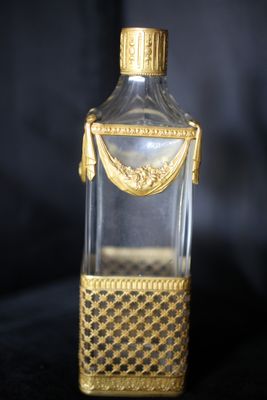 une bouteille en verre à l'ancienne, ornée d'une bordure dorée et d'une poignée dorée