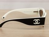 chanel sunglasses with black and white frames on a wooden table