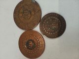 three copper coins sitting on top of a table next to each other