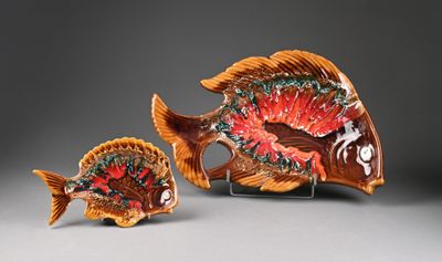 two small ceramic fish figurines on a stand on a gray surface