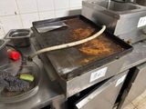une grande poêle en métal posée sur une cuisinière, avec une spatule dedans