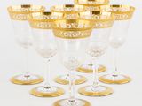 six verres à vin à bordure dorée sont alignés sur une surface blanche