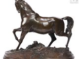 bronze statue of a horse running on a rock with a white background