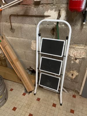 une échelle appuyée contre un mur, à côté d'un seau