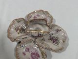 a small white and purple flower brooch on a white table