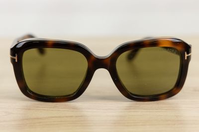 sunglasses on a wooden table with a white wall in the background