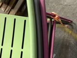 une personne assise sur une chaise verte à côté d'une pile de chaises en plastique