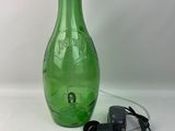 une image représentant une bouteille en verre verte à laquelle est relié un cordon d'alimentation