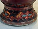 a red vase with a black and blue design on it