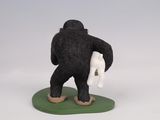 figurine of a black gorilla holding a white bag on a green base