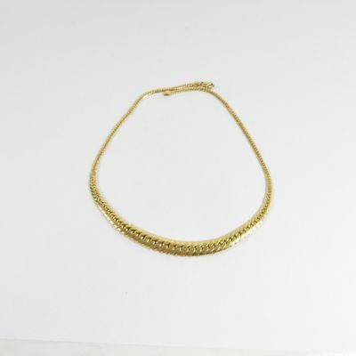 un collier en or posé sur une surface blanche