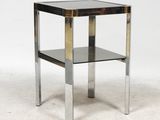 un gros plan d'une table d'appoint en métal et en verre posée sur une surface blanche
