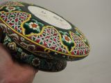 a hand holding a decorative box with a design on it