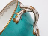 a blue vase with a gold handle on a white table
