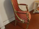 une chaise rouge et dorée dans un coin de la pièce