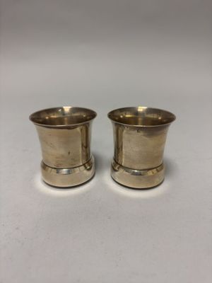 deux tasses en métal argenté posées sur un fond blanc