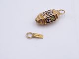 a small gold charm with a flower design on it