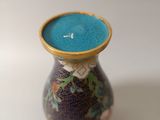 a small vase with a blue lid sitting on a white surface