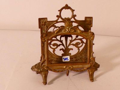 une petite horloge en or posée sur un socle, sur une surface blanche