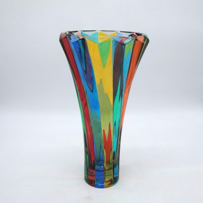 un vase en verre aux couleurs vives posé sur une surface blanche, avec un fond blanc