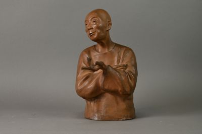 une petite statue représentant un homme les bras croisés