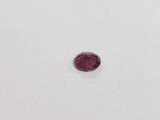 an oval shaped pink sapphire stone on a white surface