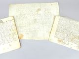 trois feuilles de papier sur lesquelles il y a des inscriptions, posées sur une table