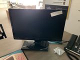 a computer monitor sitting on a desk next to a telephone