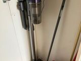 two vacuums and a mop in the corner of a room